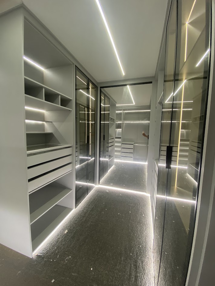 Closet branco com portas de vidro e iluminação em LED